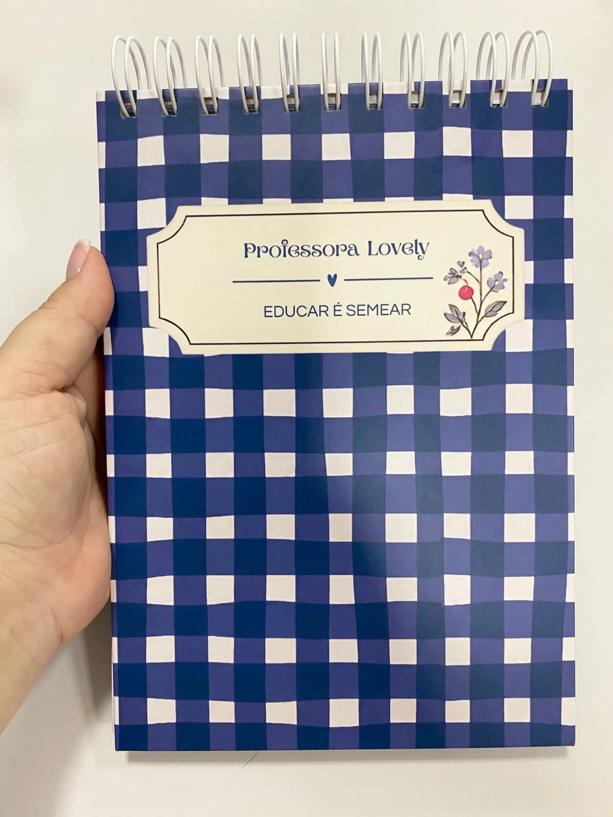 Capa xadrez de azul marinho com branco, com etiqueta com o nome da professora